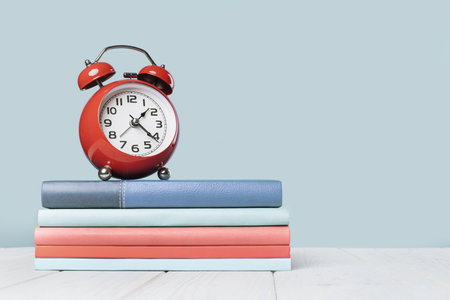 Organized office and school orange and pastel blue stationery, notebooks books and alarm clock on...