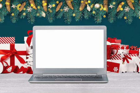Front view of the laptop with mockup screen on the desk. Christmas gifts and decorations behind...