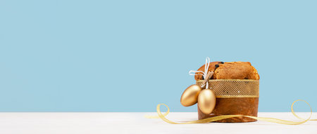 Happy Easter banner. Italian Easter Decorated Panettone and golden eggs on white table and festive...