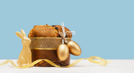Happy Easter banner. Bunny and Italian Easter Decorated Panettone and golden eggs on white table and...