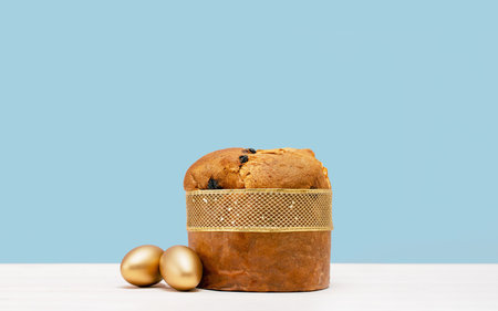 Happy Easter banner. Italian Easter Decorated Panettone and golden eggs on white table. Wide banner...