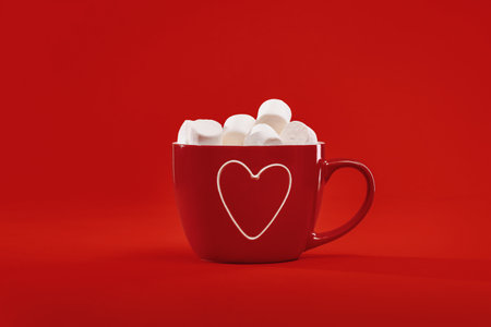 Red gift hot chocolate mug with heart and marshmallows on red background. Happy St Valentines sweet gift. Thank you. Mothers Day. Love concept monochromeの写真素材