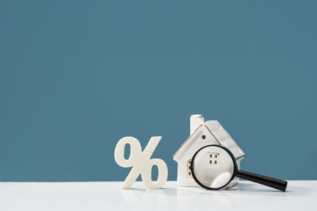 Percentage with magnifying glass and house on white desk. mortgage calculator or real estate business concept. Listing. Down payment. Loan or insurance rate payments. Liability and riskの写真素材