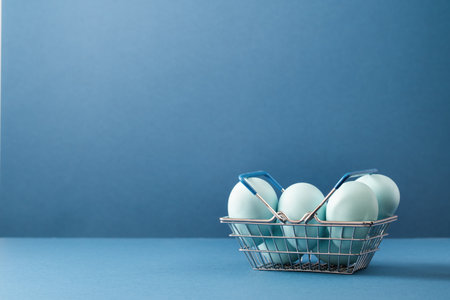 Several blue dyed Easter eggs in metal basket. Monochrome on blue. Easter holiday eggs hunt and...
