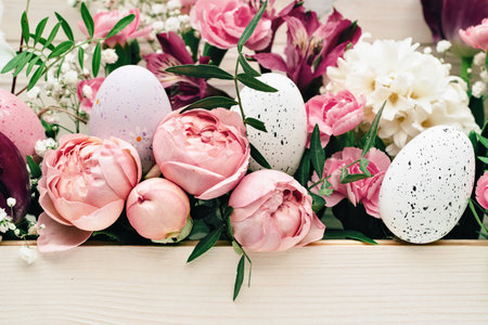 Easter eggs with beautiful rich bouquet of spring flowers on wooden background. Happy Easter full frame pink flowersの写真素材