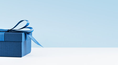 Part of Luxury gift box with a blue bow on light blue. Side view monochrome . Fathers day or Valentines day gift for him. Corporate gift concept or birthday party. Festive sale copy space bannerの写真素材