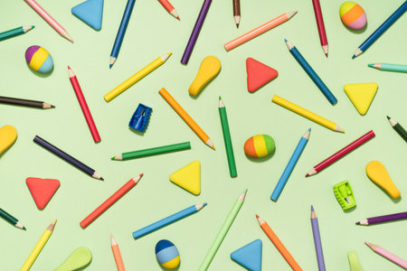 Colored Pencils and rubber erasers background pattern on light green. Back to School or drawing and creativity concept. Copy space in center. Top viewの写真素材