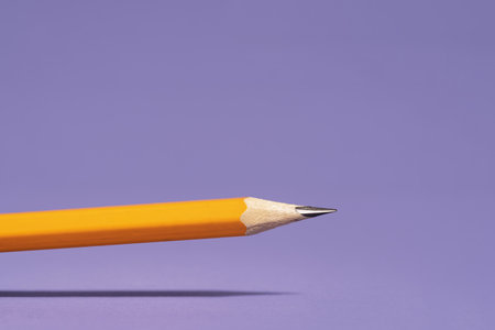 orange pencil with shadow above lilac background. Office or school stationery. Back to school. Drawing writing or storyteling concept. notes taking. meetingの写真素材