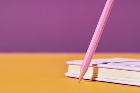pink pencil tip touching orange desk on magenta lilac background with diary or copybook. Office or school stationery. Back to school. Drawing writing or storyteling concept. notes taking. meetingの写真素材