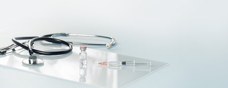 Medical or healthcare concept banner. stethoscope on on a gray desk with a syringe and vial. Vaccination, flu covid rsv jab. Tridemic. Doctor appointment or checkups schedule, PPE. Copy space. Bannerの写真素材