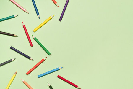 Colored Pencils background pattern on light green. Back to School or drawing and creativity concept. Copy space in center. Top viewの写真素材