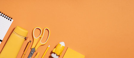 Assorted office and school white and yellow stationery on orange. back to school or education craft office work concept. Bright Yellow monochrome scissors, rocket notepad. Achievement and successの写真素材