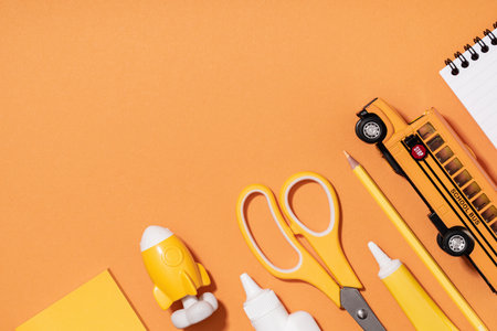Assorted office and school white and yellow stationery on orange. back to school or education craft office work concept. School bus with scissors, rocket notepad. Achievement and successの写真素材