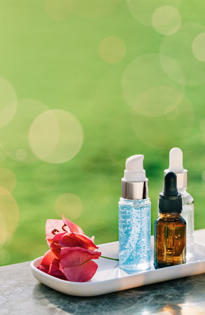 Natural medicine or aroma oil or beauty essence concept mockup three vials with dropper with droplet on tray with red flower. Face and body spa serum care fresh conceptの写真素材