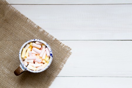 Cup of colorful marshmallows on the white wooden table, top viewの写真素材