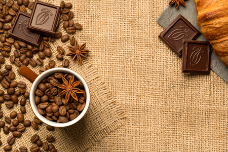 Cup of coffee with chocolate, cinnamon on burlap backgroundの写真素材