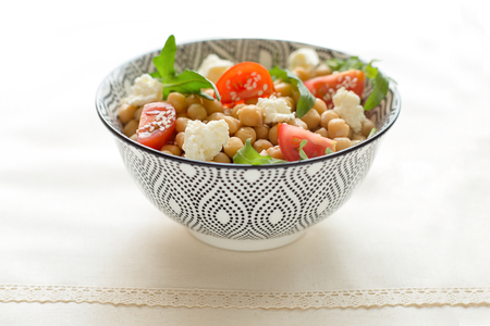 Fresh organic salad with chickpeas, arugula, tomatoes, rustick table, white background, close upの写真素材
