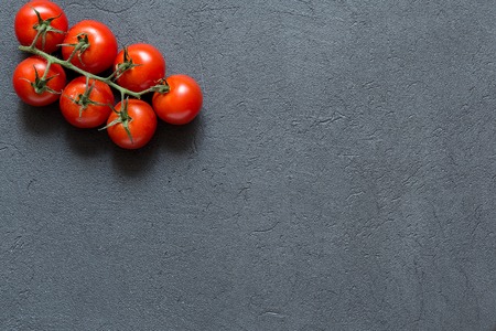 Fresh cherry tomatoes on a stone dark background, top view, copy space.の写真素材