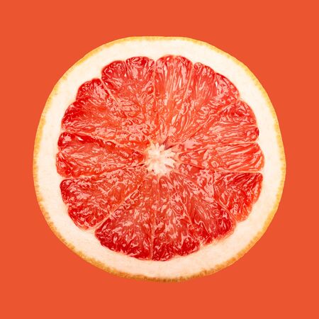 A slice of grapefruit isolated on red background, close upの写真素材
