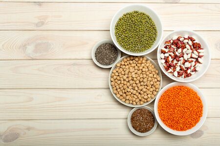 Veggie protein source. Legumes lentils, chickpea, mung bean, bean, flax seed, chia on bowls on white...