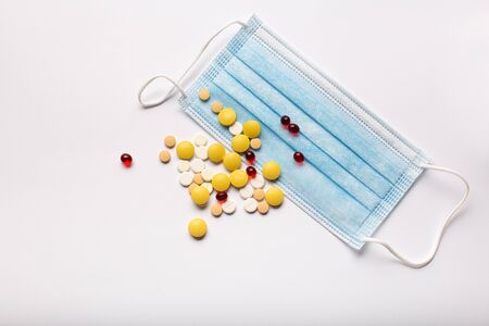 Top view blue medical mask protection, colored pills and capsules on white background, copy spaceの写真素材