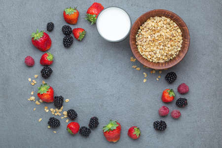 Strawberry and blackberry frame on grey background. Creative round frame made of berries, granola...