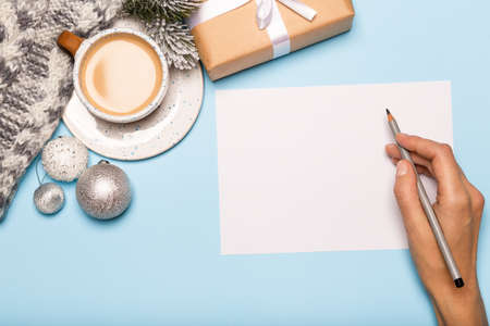 Hand writing christmas card, paper gift box and coffee on blue background, goals conceptの写真素材