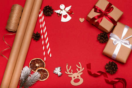 Christmas red background with gift boxes, paper's rools and decorations. Preparation for holidays. Top view copy spaceの写真素材