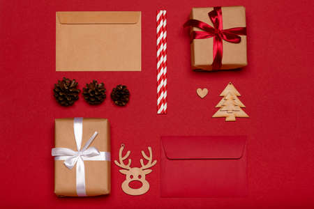 Christmas composition. Christmas gifts, wooden toys, pine cones on red background top viewの写真素材