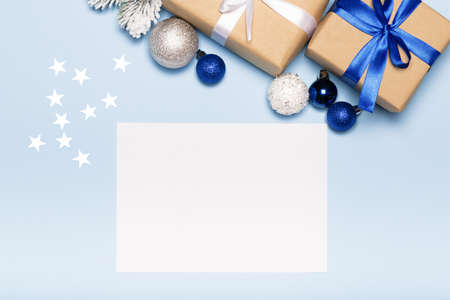 Christmas card with paper gift box and balls on blue background holiday mockup top view, flat layの写真素材