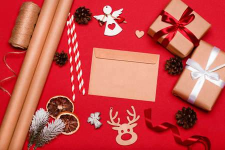 Christmas composition. Christmas gifts, decorations, envelope on red background. Top view, flat lay.の写真素材