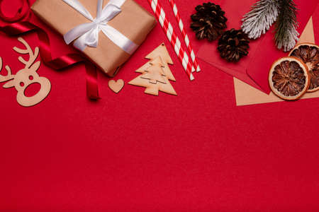 Christmas composition. Christmas red decorations, gift box, fir tree branches on red background....