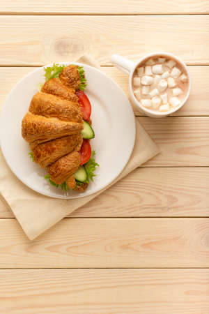Vegan croissant sandwich and hot chocolate on wooden board top view, healthy vegetarian food conceptの写真素材