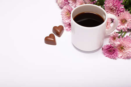 Flowers composition. Close up of coffee cup, flowers and sweets on white background top view, copy spaceの写真素材