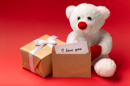 White teddy bear with hearts and gift box on red background, Valentine's day close upの写真素材