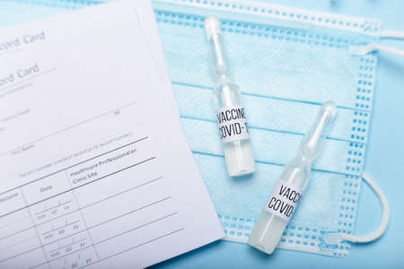 Vaccination record card with equipment on blue