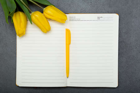 Morning productivity, happy monday concept. Notebook with empty list and yellow tulips.の写真素材