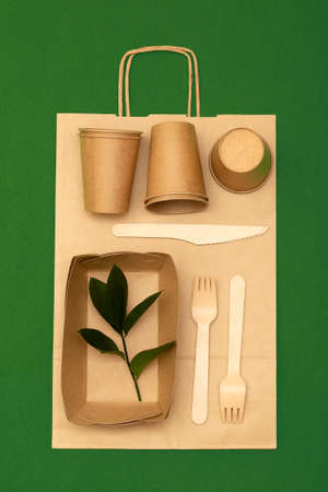 Eco-friendly disposable bamboo utensils wood and paper on green background. Zero waste and plastic...