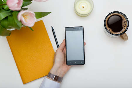 Mockup image of cell phone in female hand. Design creative work space top view, templateの写真素材