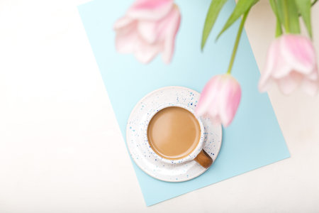 Coffee mug and flowers, morning coffee on white table from above, cozy and tasty breakfast.の写真素材