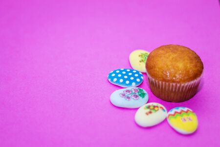 on a pink background close-up of colored Easter eggs and cupcake, holiday background