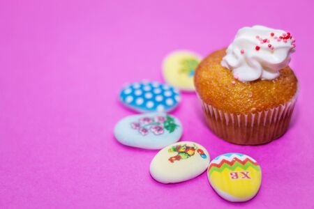 on a pink background close up of colored Easter eggs and cupcakeの写真素材