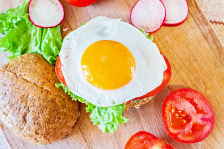 A healthy breakfast. Bun with lettuce, tomatoes and egg close-up.の写真素材