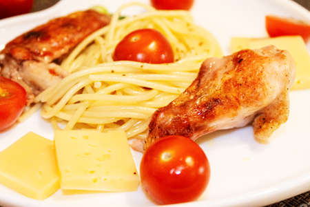 Spaghetti with cherry tomatoes, cheese and fried chicken on a close-up plateの写真素材