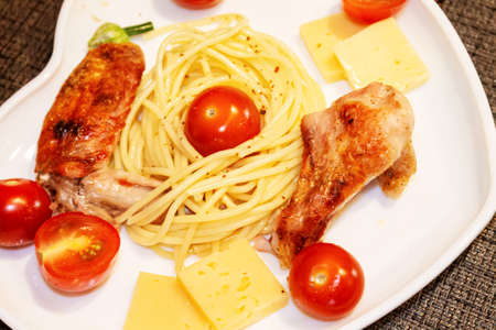 Spaghetti with cherry tomatoes, cheese and fried chicken on a close-up plateの写真素材