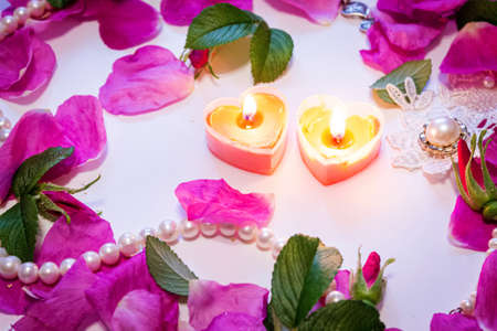 Romantic background. On a white sheet rose petals, decorations and candles close-up.の写真素材