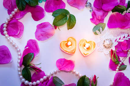 Romantic background. On a white sheet rose petals, decorations and candles close-up.の写真素材