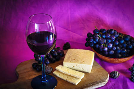 A glass of red wine with cheese and grapes close-up.の写真素材