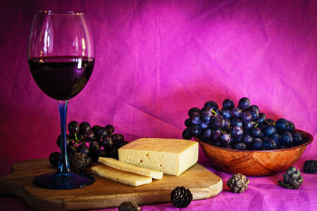 A glass of red wine with cheese and grapes close-up.の写真素材