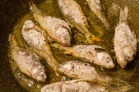 River fish is fried in a frying pan close-up.の写真素材